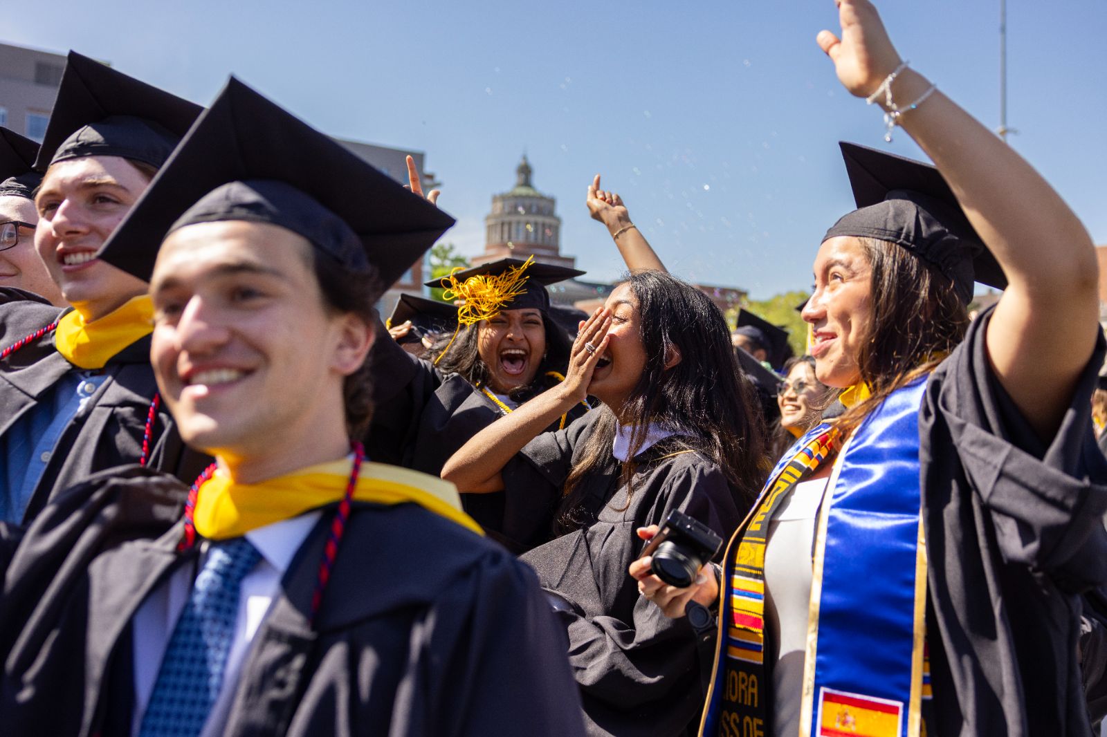 University of Rochester graduates joyfully celebrate their graduation with caps and gowns in a festive atmosphere.