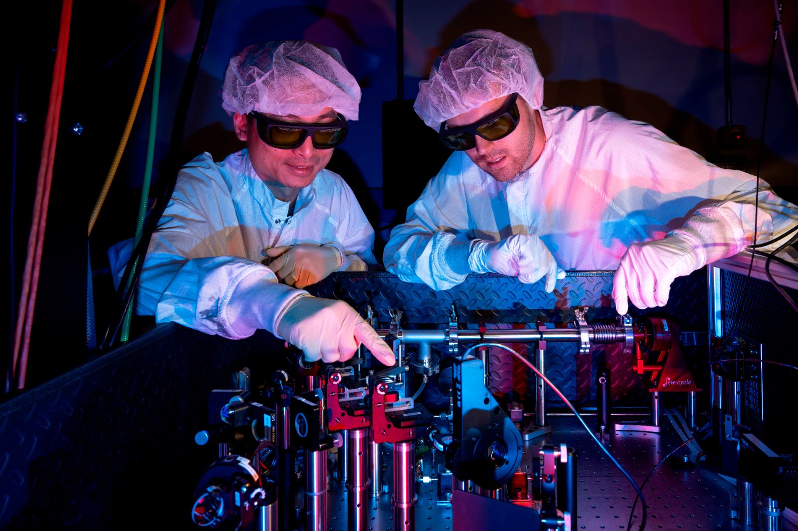 Two men in white lab coats operate a machine in a University of Rochester laboratory.
