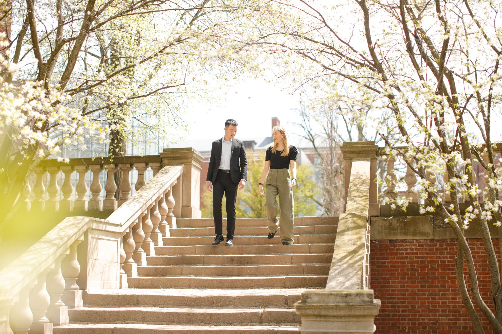 Two University of Rochester students walking up the stairs in front of a building on campus.